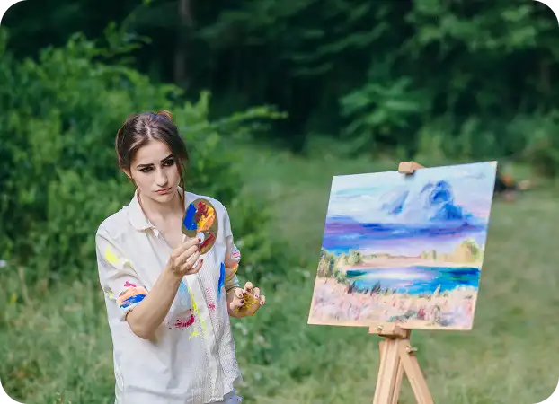 A girl in the park is painting a colorful Mountain and Lake Composition on a canvas on an easel, holding a palette.